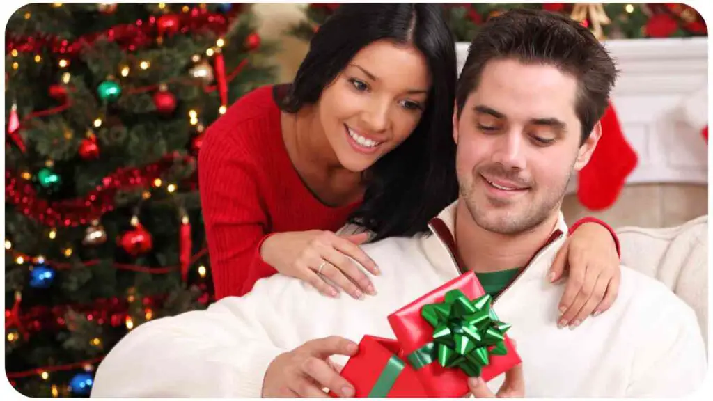 a man and woman sitting on a couch with a christmas tree in the background