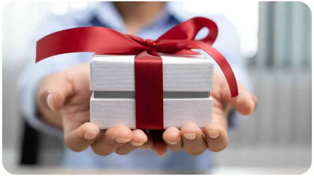 a person holding a gift box with a red ribbon