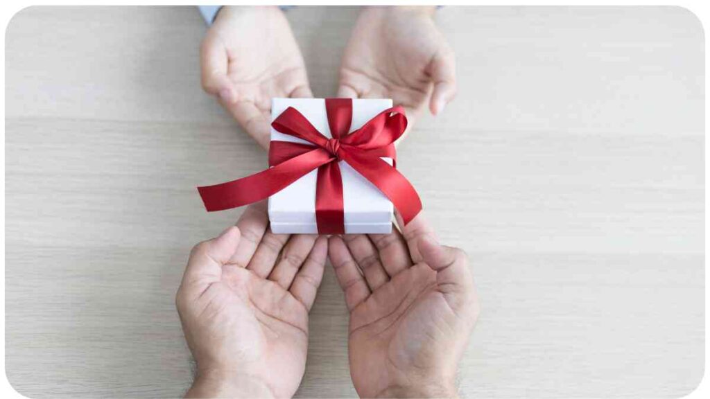 two hands holding a gift box with a red ribbon