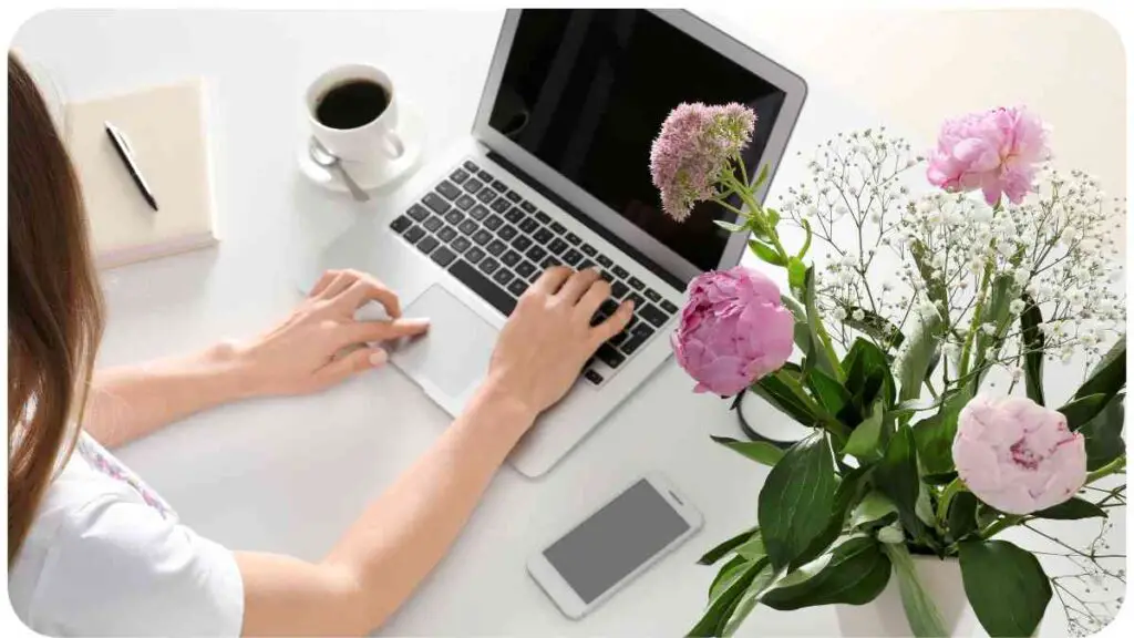 a person typing on a laptop with flowers in front of them